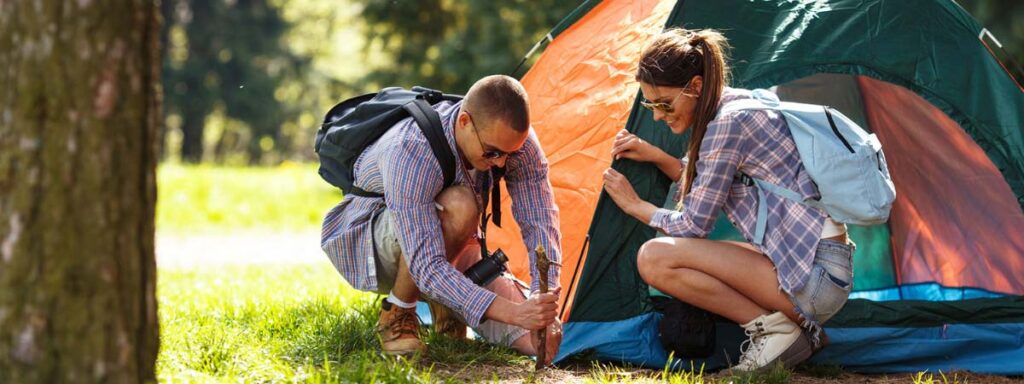 A young man and woman setting up a tent while camping