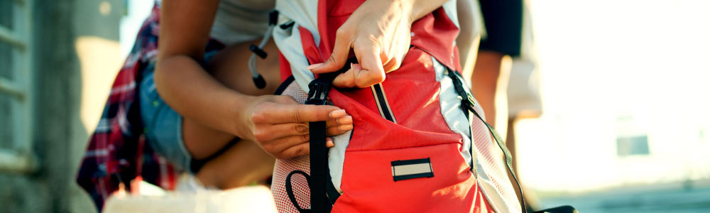 Person adjusting strap on a red backpack