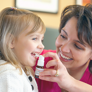 young girl taking allergy drops